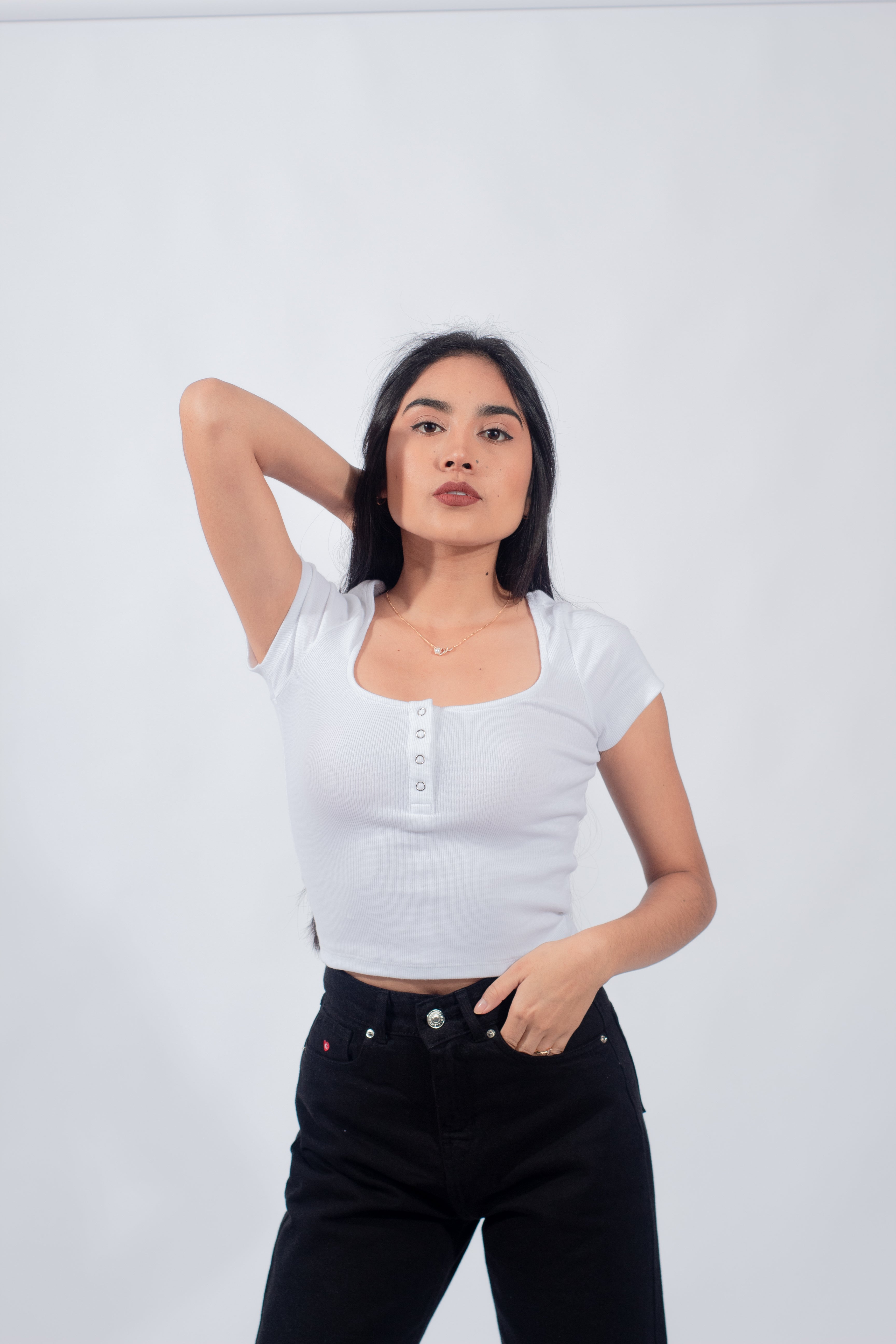 Mujer joven vistiendo un polo básico con botones de color blanco, reflejando una estética casual y minimalista.