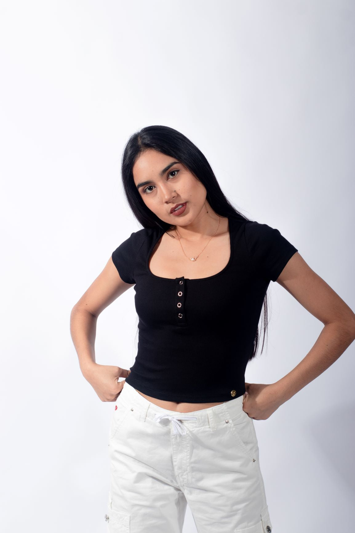 Joven estilizada llevando un polo básico con botones de color negro, representando un estilo casual y minimalista.