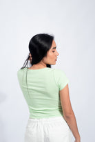 Mujer joven luciendo un polo básico con botones de color verde menta, para un look casual y minimalista.